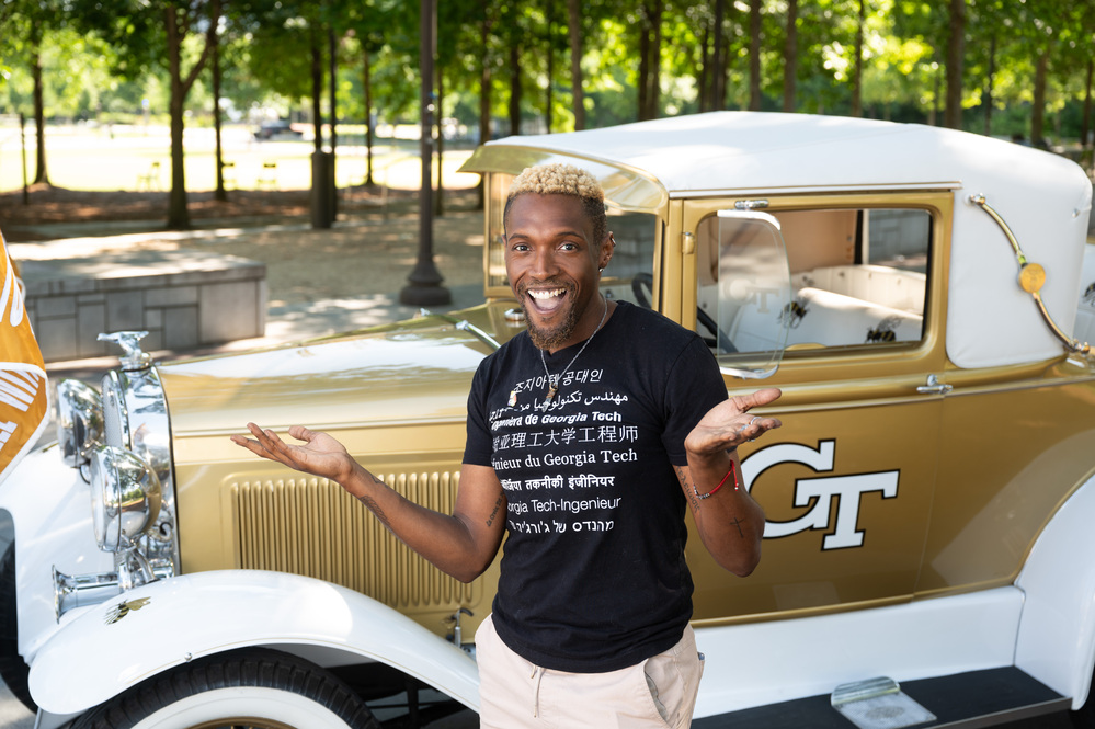 A person stands at a Model T car with the GT logo
