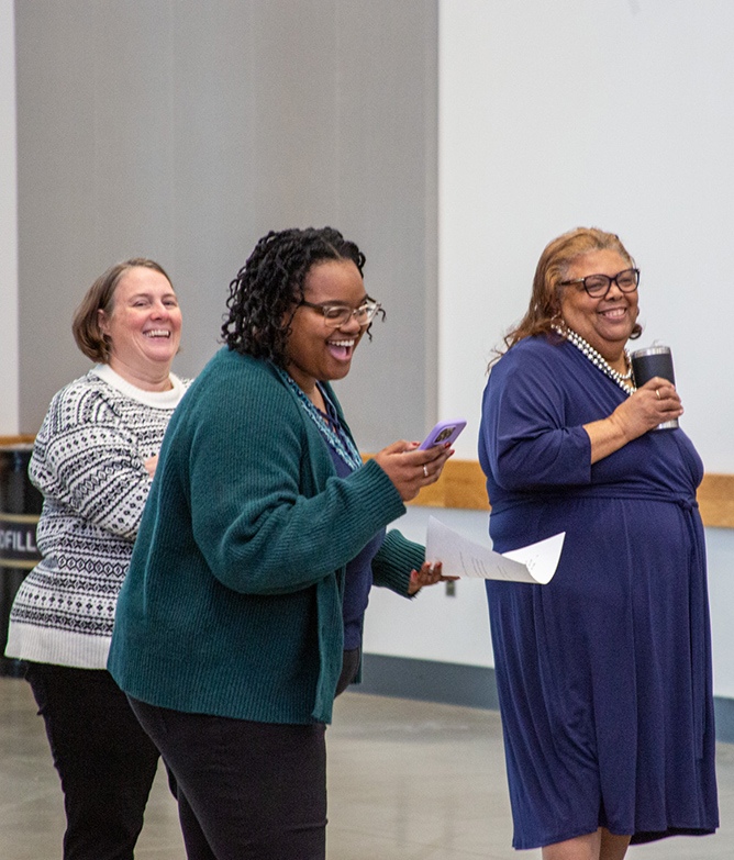 three women standing and laughing