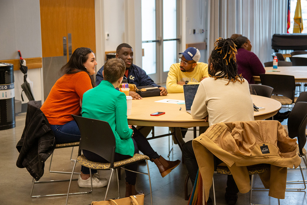 People engaged in conversation sit at a round table