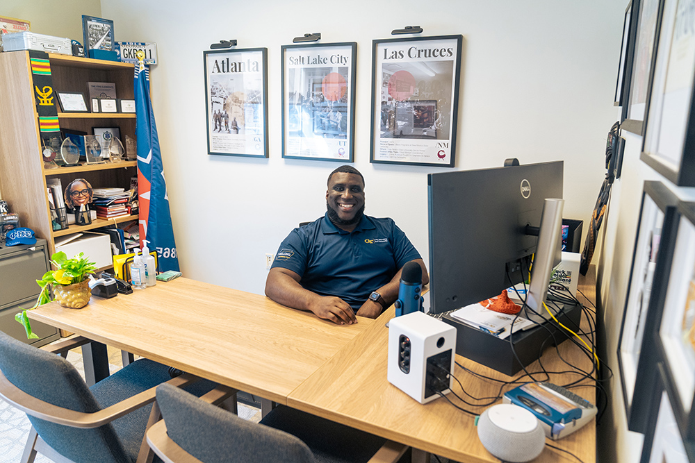 A person with a friendly smile sits at a desk 